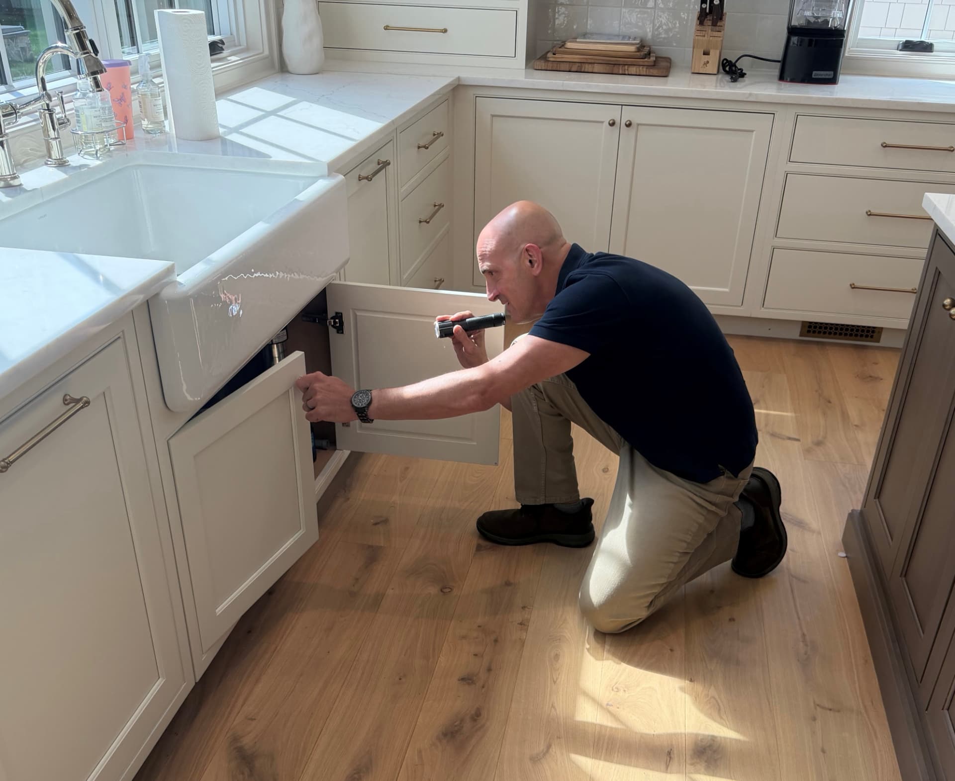 Robert looking for moisture beneath a farmhouse kitchen sink